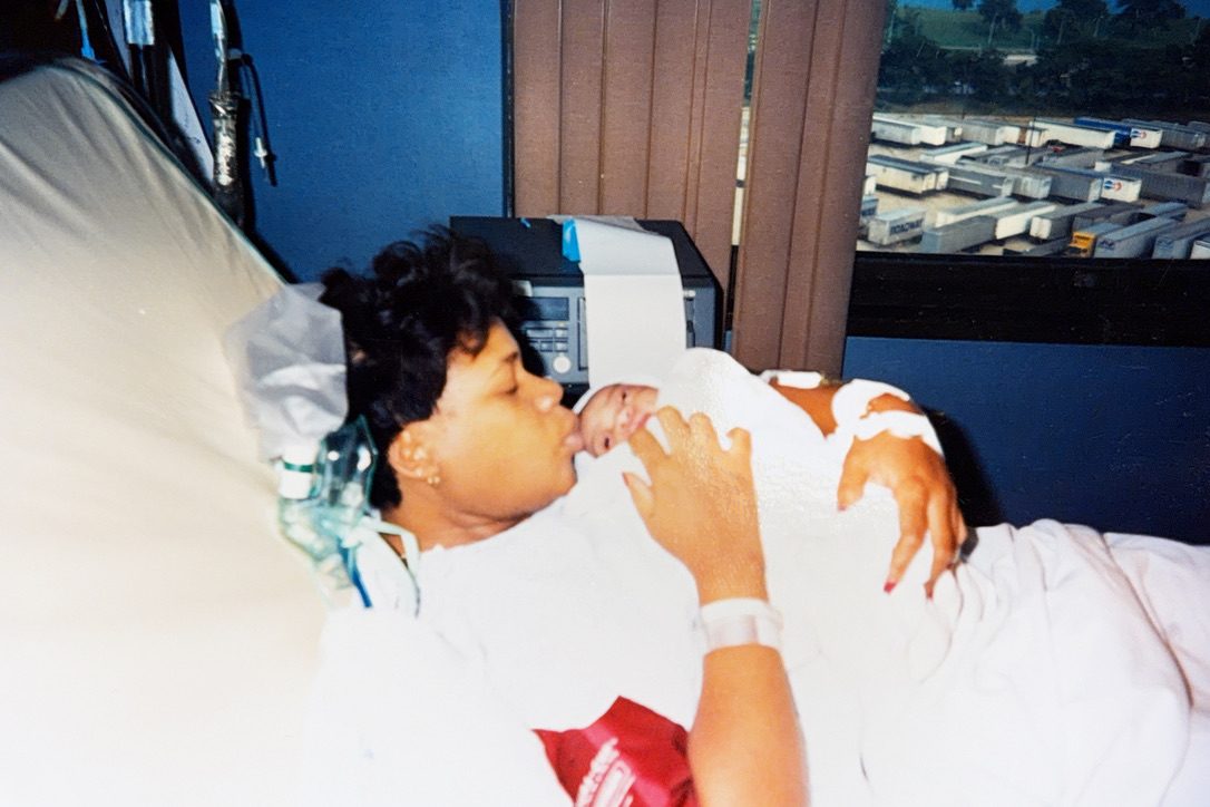 Donna Jean in a hospital bed kissing her newborn son